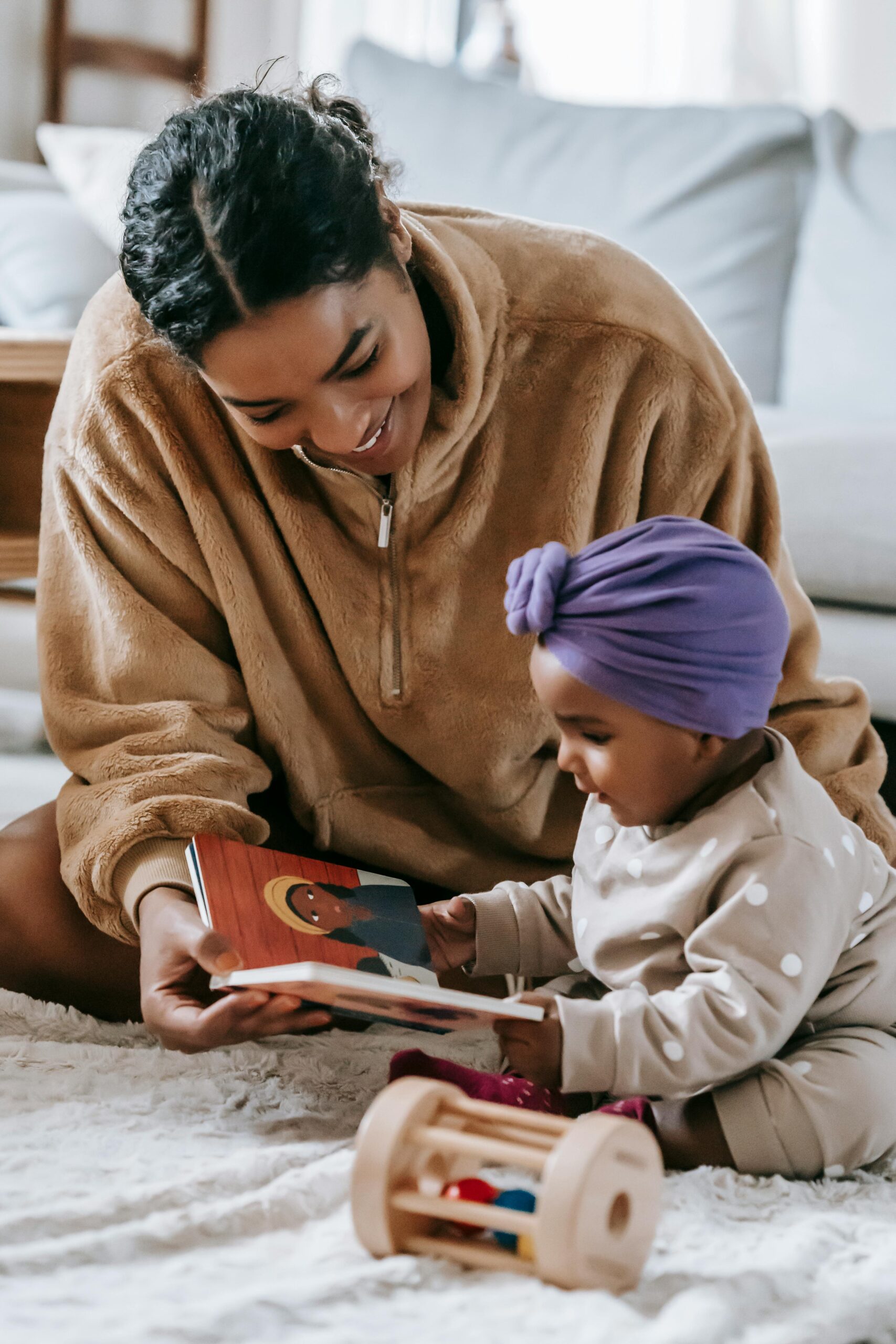 A mother and her baby enjoying a bonding moment while reading indoors.