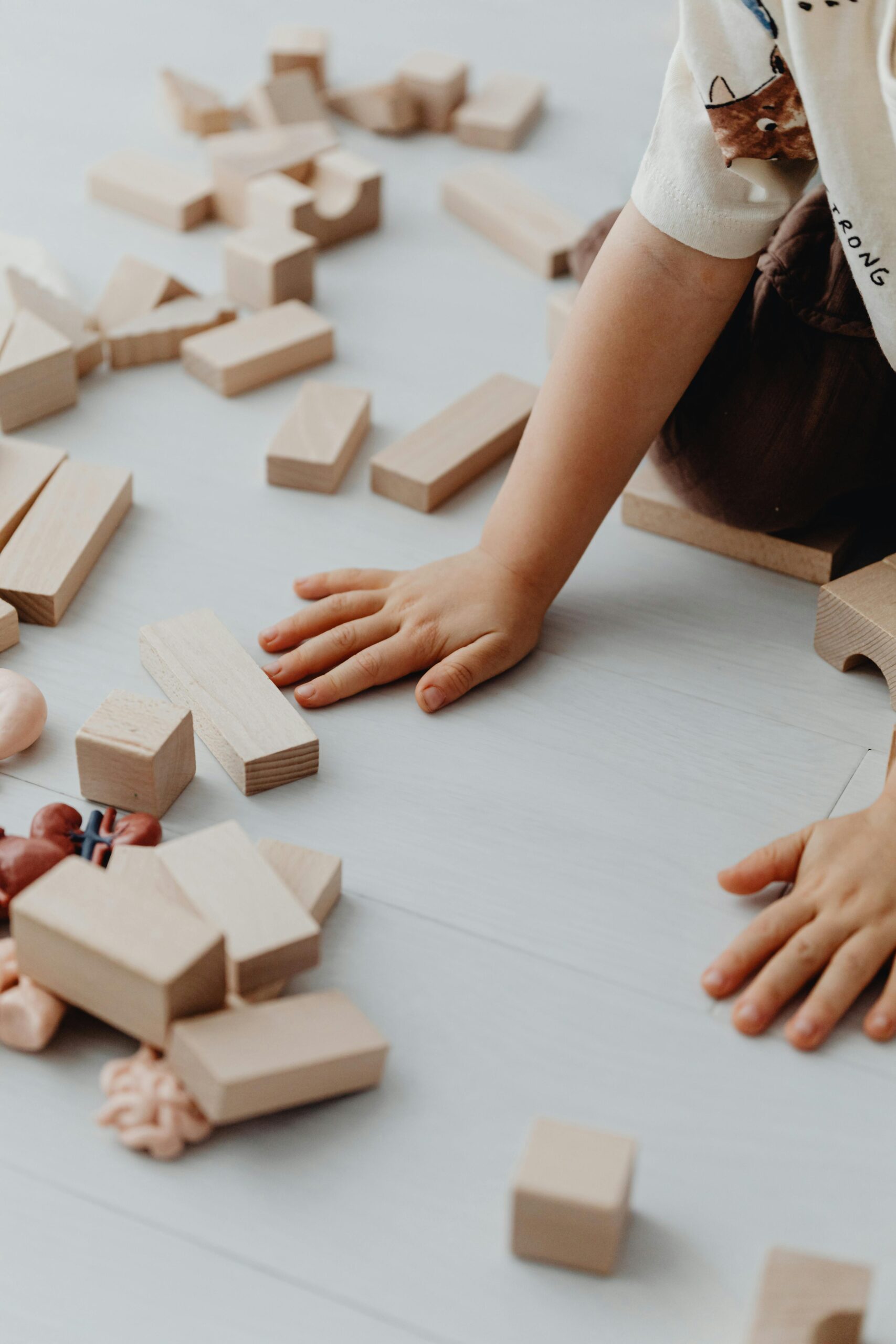 A child playing with various wooden blocks on the floor, fostering creativity.