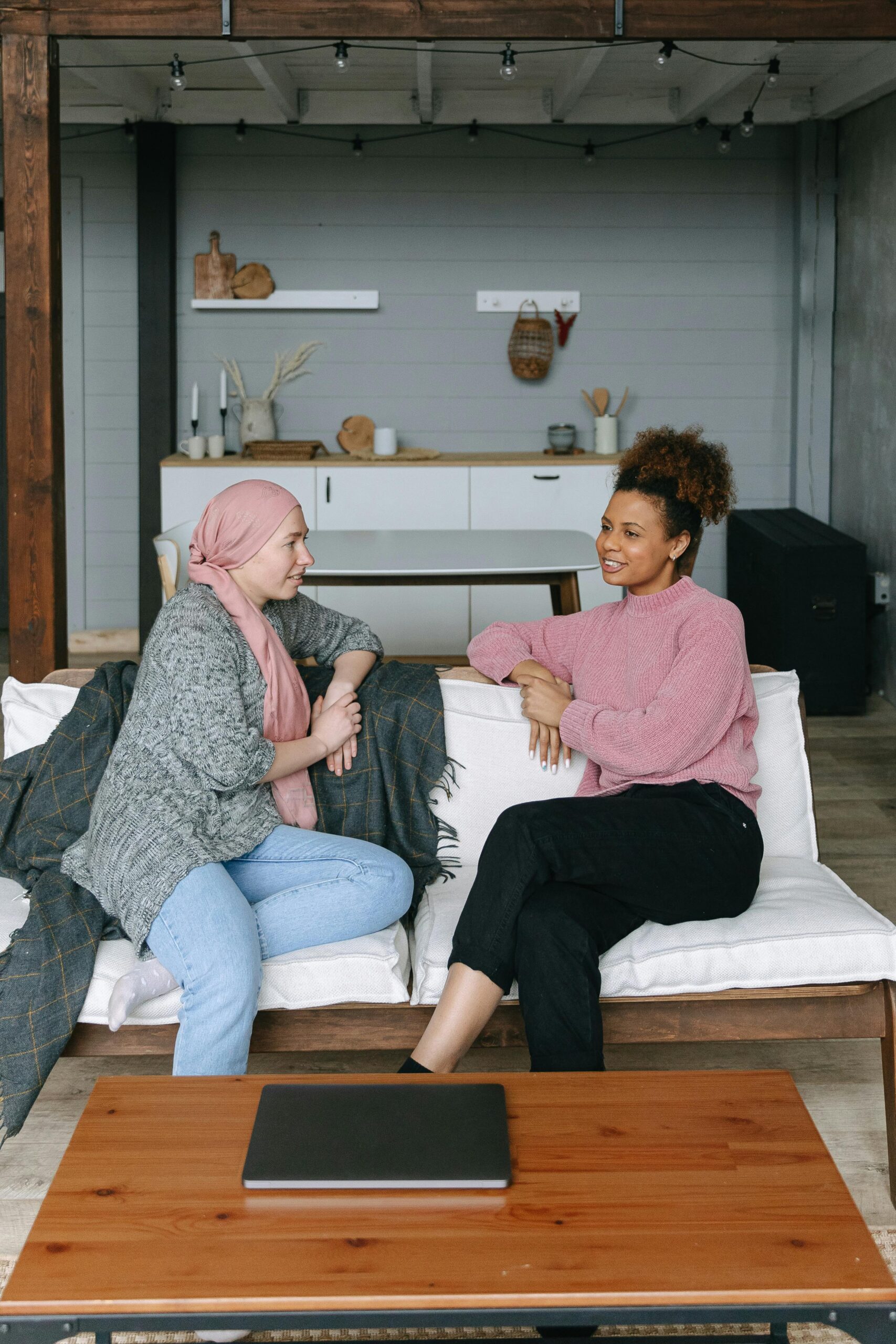 Two women having a heartfelt conversation on a couch, symbolizing support and friendship.