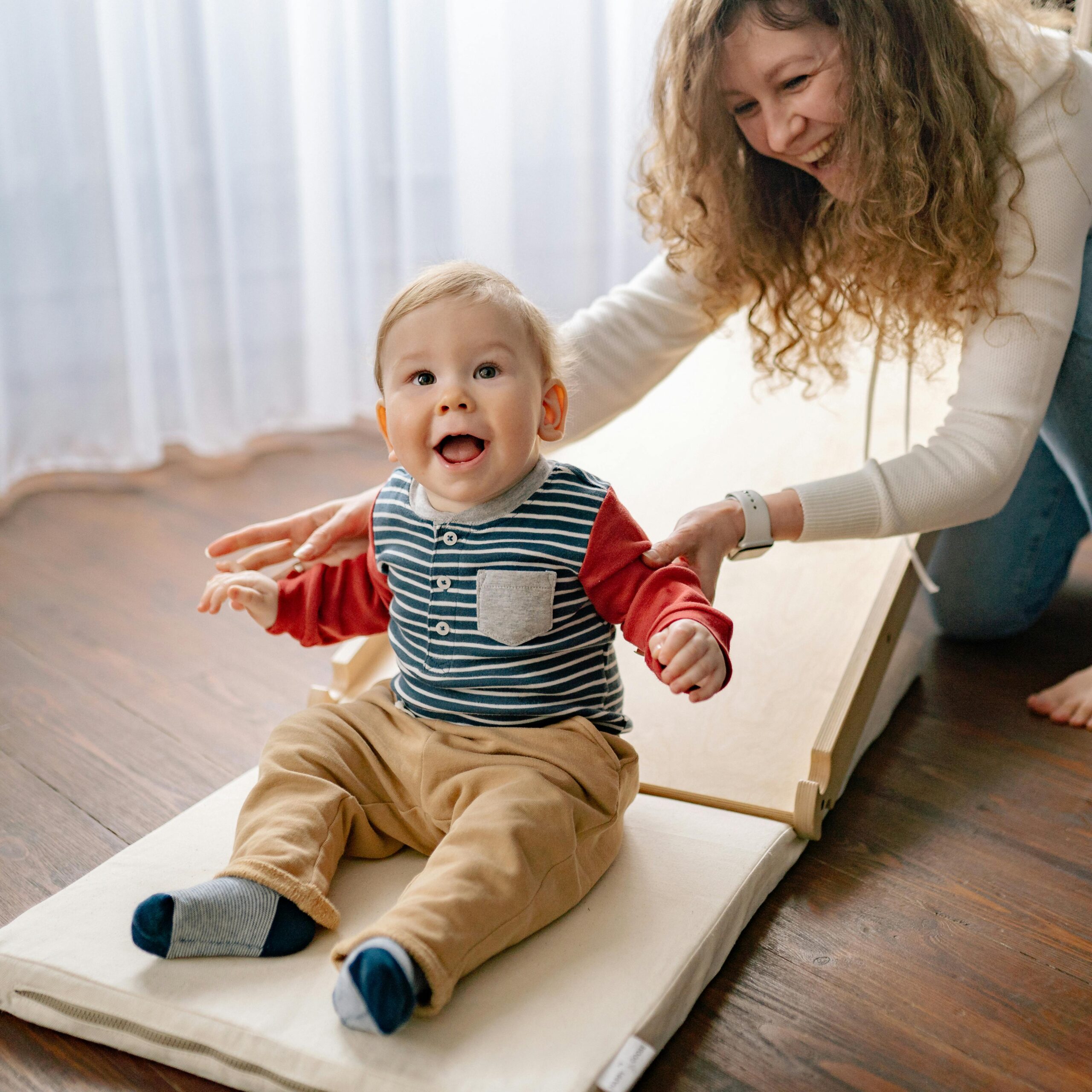 Happy mother and baby enjoying playful moments indoors, creating joyful memories.